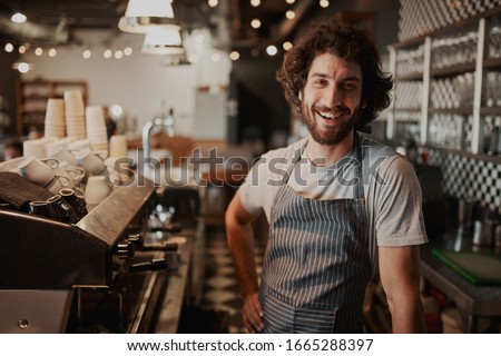 Portrait of handsome young male coffee shop owner standing behind counter Royalty-Free Stock Photo #1665288397