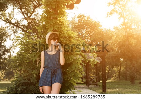 Cute young woman posing outdoors in summertime sunlight.
