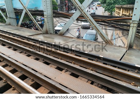 Railways on Long Bien ancient metal bridge with street traffic on background