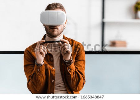 3d visualizer using virtual reality headset and holding stylus of graphics tablet near computer monitors in office