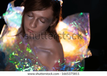 Artistic portrait of a beautiful girl with silver make-up. With a luminous dress from a color film