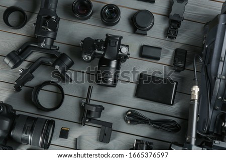 Flat lay composition with video camera and other equipment on grey wooden table