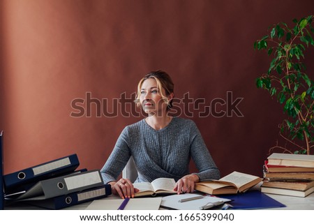 woman in business suit at the desk at work in the office with books