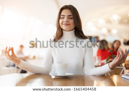 young beautiful womansitting in yoga position in cafe during lunch time, peace and relax concept