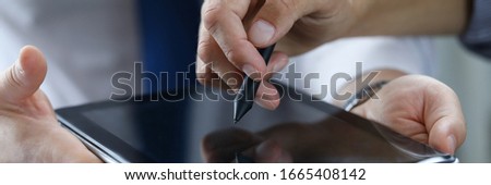 Focus on male hands holding modern tablet. Business partner showing something with stylos. Empty copy space on gadget display. Biz meeting concept. Blurred background