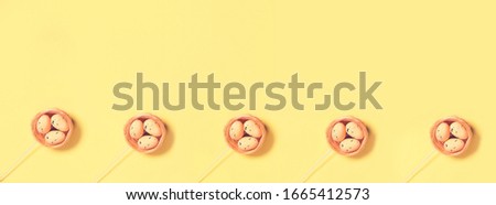 Decorative Easter eggs in nest on yellow background. Copy space. Top view