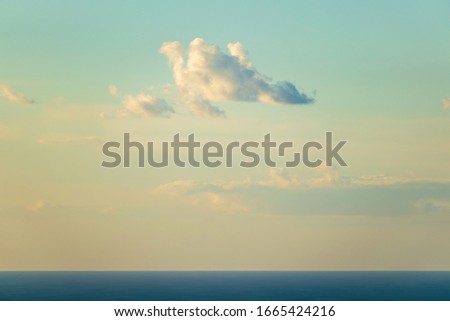 View of cloud flying over dark blue ocean surface in yellow evening light