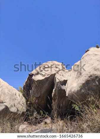 The picture contain blue sky and rocks of a small hill. 
