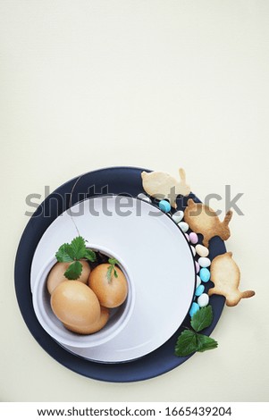        Happy  Easter eggs with green leaves of strawberries, bunny-shaped cookies and colored sweets on a light background. Copy space                  