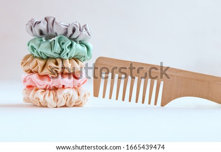 Wooden hairbrush and Lot of Colorful silk Scrunchies on white. Luxury Hairdressing tools and accessories. Hair Scrunchies, Elastic HairBands, Bobble Sports Scrunchie Hairband Royalty-Free Stock Photo #1665439474