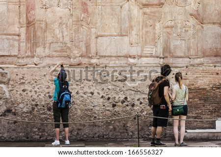 tourists look at details of roman frescoes in Pompeii, Italy