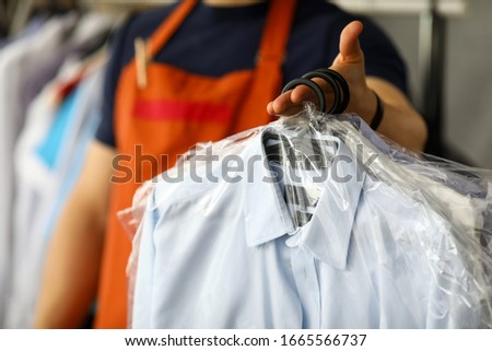 Clothes dry cleaning service worker returning shirts to customer close-up Royalty-Free Stock Photo #1665566737