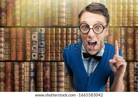 Young nerd man posing on bookshelf background