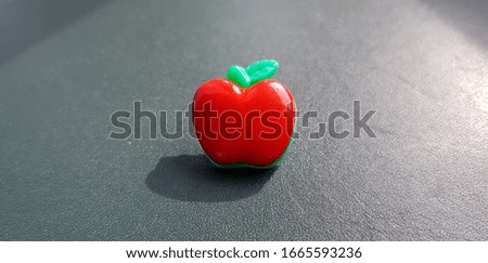 A small decorative red apple on a dark background.
