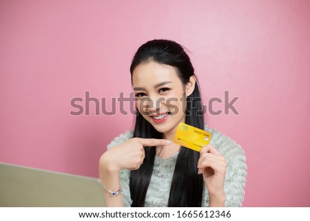 beauty asia smiley woman pointing cerdit card pink background.