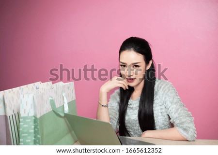 beauty asia smiley woman use notebook laptop with shopping bags on table pink background.