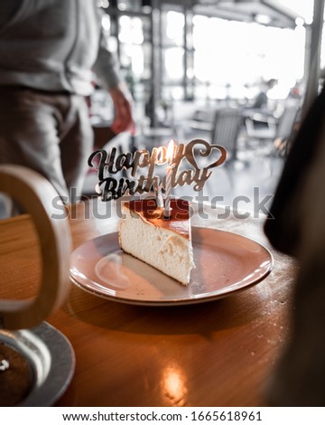 Slice of a cheesecake with "happy birthday" sign on it.
Served on the table in the cafe.
