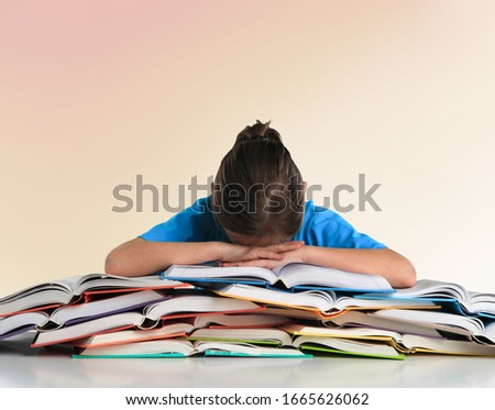 Sad tired student girl sitting at the table with many books