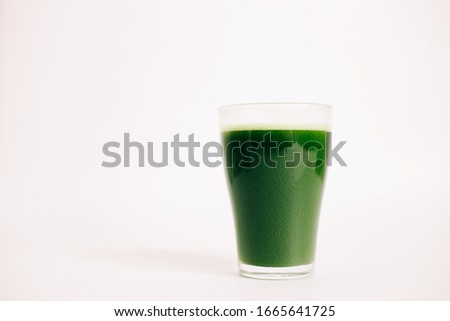 green freshly squeezed juice of green Apple and young spinach leaves on a white background
