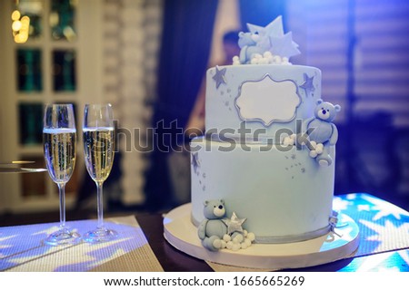 Little boy party cake with sweet bears on the table. Two glasses with champagne