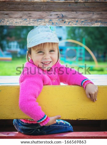 Little kid in the playing lodge in the playground.