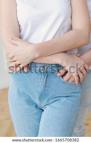 guy in light jeans from behind hugs a girl in light jeans
