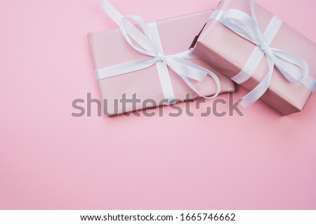 two pink wrapped presents lying on pink background, with copy space