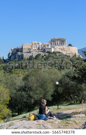 Young woman tourist at Pnyx with Parthenon temple and Acropolis hill in the background