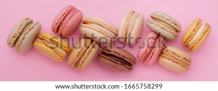 Colorful traditional french macaroons cookies, over pink background with copy space. Banner.