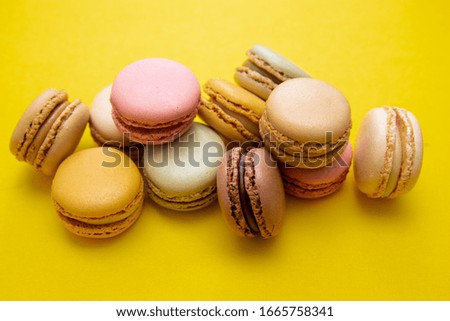 Colorful macaroons cookies, over yellow background with copy space. Traditional french dessert, abstract background.