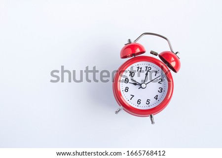 Red alarm clock on the white  background.  Top view. Copy space. Closeup.