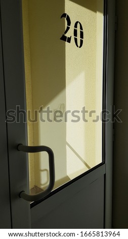 Plastic door with glass window and blurred reflections of yellow wall and geometric shape shadows from bright sunlight. Modern architecture details.