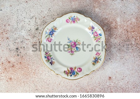 Antique porcelain dish with painted flower bouquetes on concrete background. Copy space for text, food photography props.