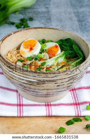 Japanese sesame ramen noodles with pok choi, boiled egg, mushrooms, spring onions and chili sauce