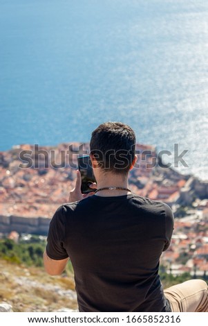 Guy taking pictures with smartphone outdoors