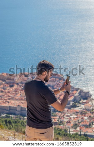 Guy taking pictures with smartphone outdoors