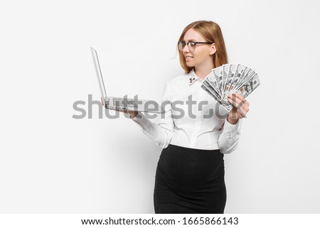 Image of a young pregnant businesswoman in glasses posing with a laptop, holding banknotes in her hands, on a white background