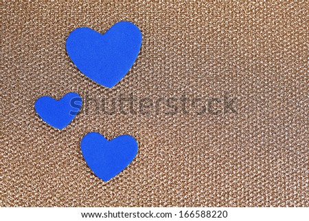 Blue hearts made of felt on golden background