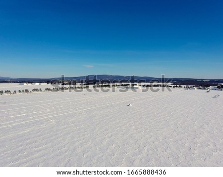 Aerial view of a snowy field covered with snow waves with mountains in the distance