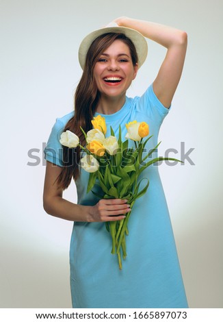 Smiling girl wearing summer hat holding yellow flowers bouquet. isolated studio female portrait.