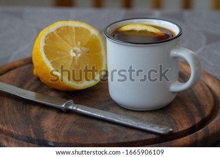 A cup of black coffee with a slice of lemon on a grey tablecloth, selective focus