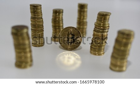 Bitcoin symbol on coin placed among six coin piles that stand around it as pillars with the reflection effect simulated by warm light under the central image