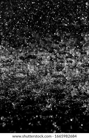 Water splashes, white bokeh, blurred background out of focus on a dark background.