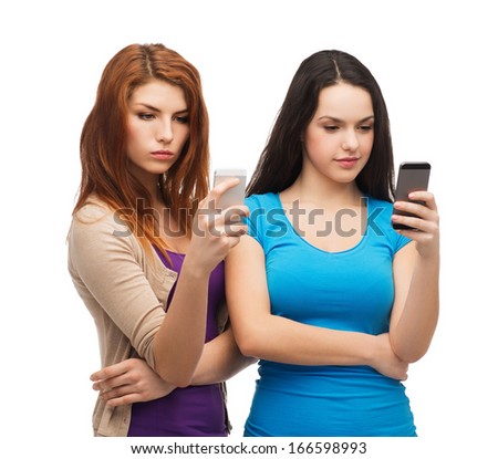 technology, friendship and people concept - two serious teenagers with smartphones