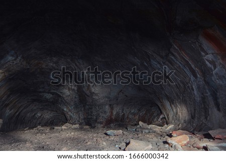 Adventure spelunking in deep dark cave with bright blue, red, and purple neon lights lighting up the cave. Hikers explore a cave in these beautiful long exposure creepy unique cavern images.