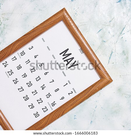 May 2020 monthly calendar placed in the wooden picture frame. View from above