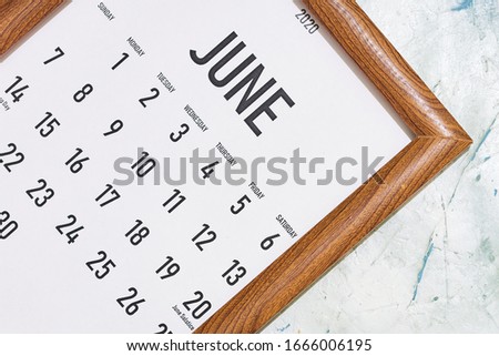 June 2020 monthly calendar placed in the wooden picture frame. View from above