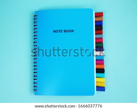School notebook with color brush pen on a light blue background