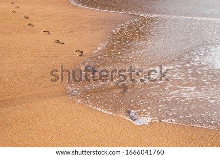 beach, wave and footprints on tropical beach at sunset time
