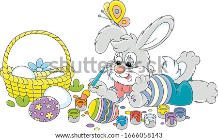 Happy little grey bunny painting beautiful ornate Easter eggs with bright and colorful paints and an art paintbrush, vector cartoon illustration on a white background